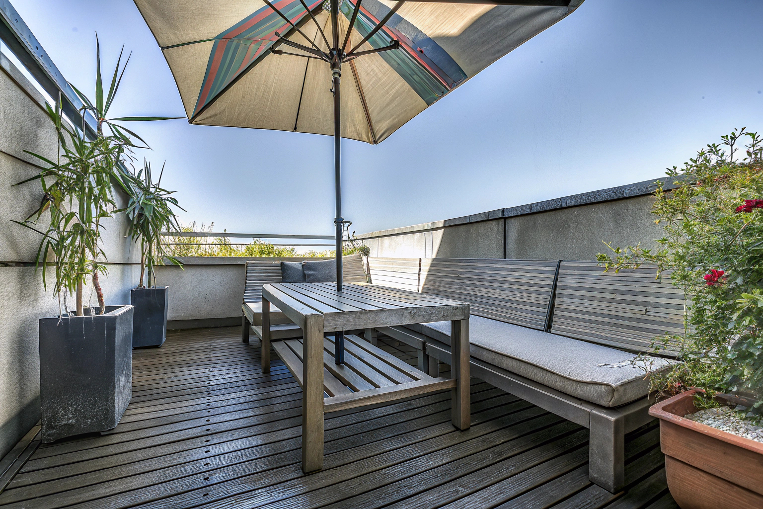Terrasse mit Sonnenschirm und Holzmöbeln